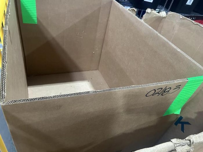 Empty cardboard storage box with green identification label and marking