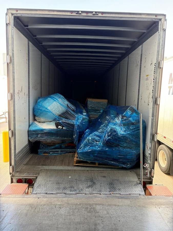 Enclosed truck trailer loaded with blue-wrapped pallets and cargo items
