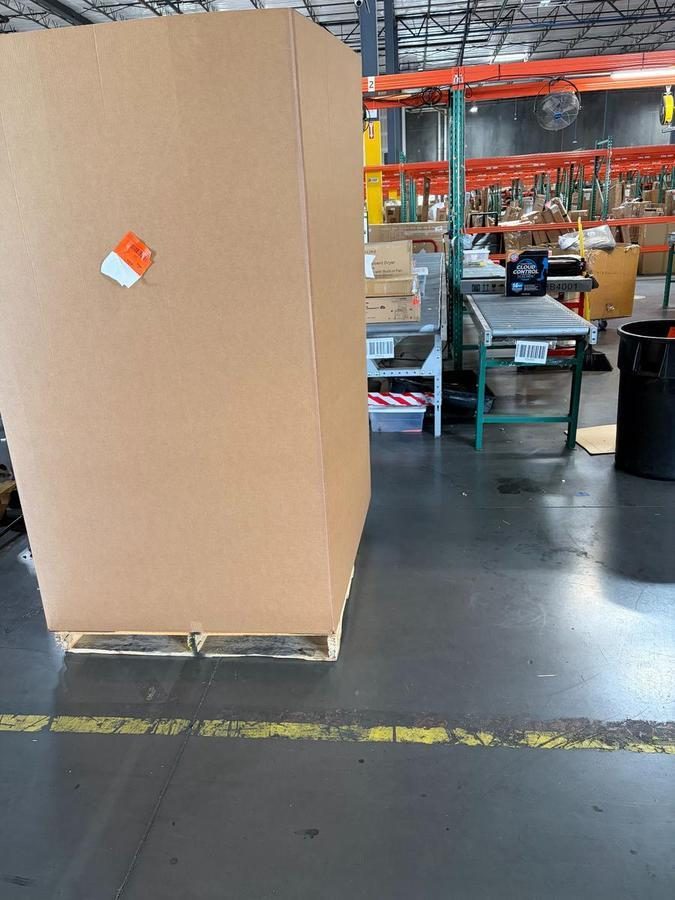Large cardboard box with orange and white label in warehouse