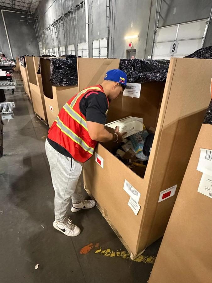 Worker inspecting contents inside large cardboard storage tote