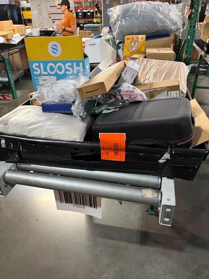 Black suitcase loaded with wrapped items on conveyor system
