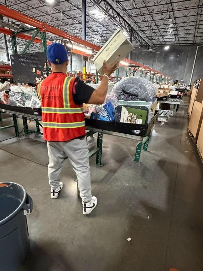 Worker sorting items on conveyor belt in warehouse facility