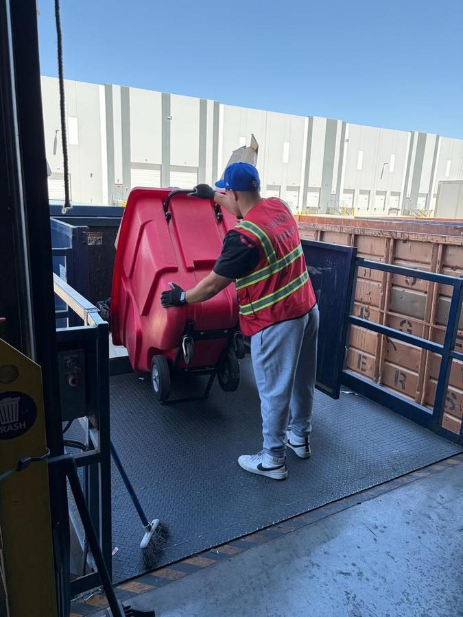 Worker securing red stroller to truck bed with straps