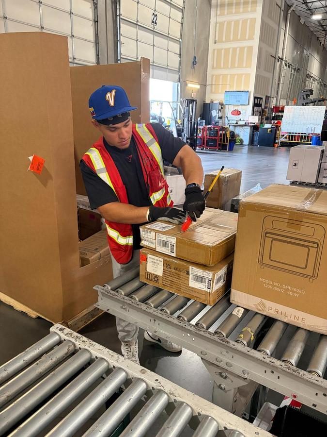 Worker processing packages on conveyor system in warehouse