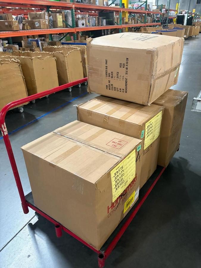 Cardboard boxes stacked on red warehouse cart with yellow labels