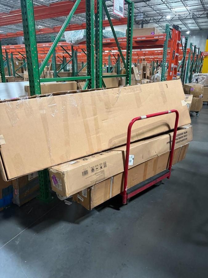 Cardboard boxes stacked on red hand truck in warehouse
