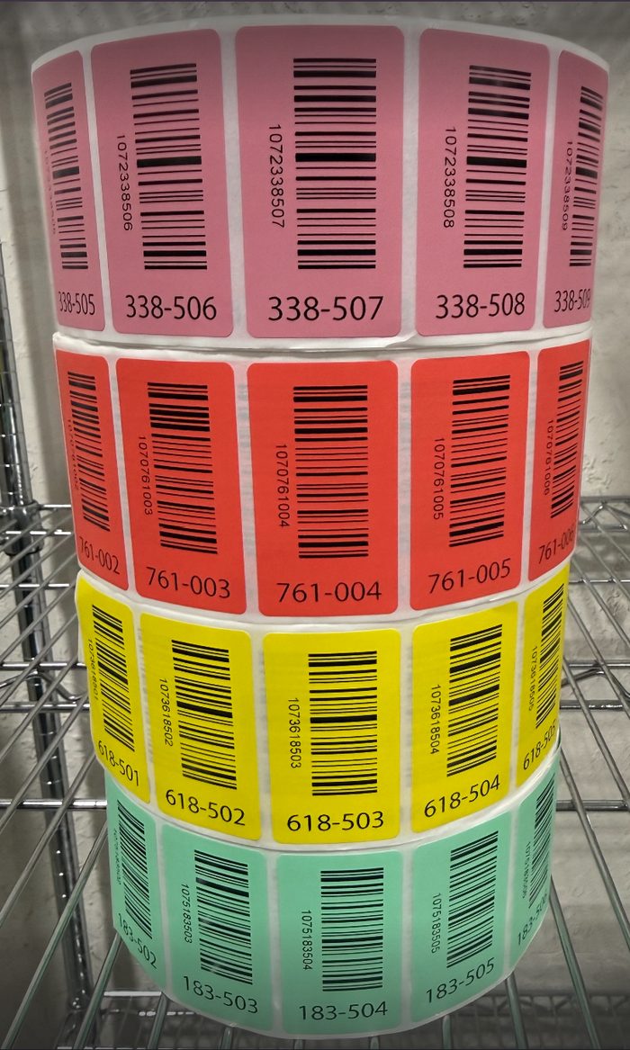 Rolls of color-coded barcode labels organized by warehouse inventory category
