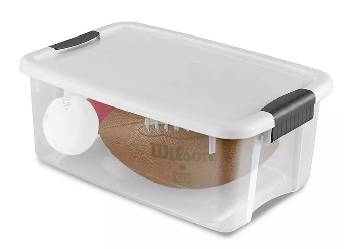 Clear plastic storage container with sports equipment and ball inside