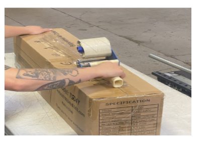 Person applying packing tape to cardboard box in warehouse