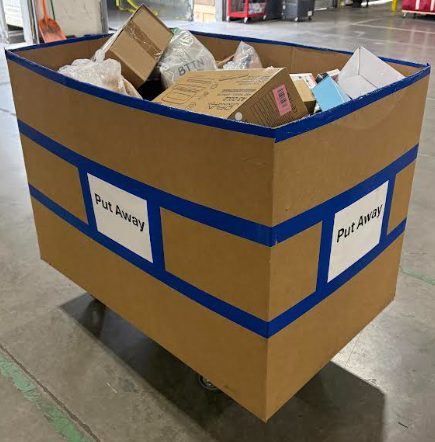 Large cardboard waste disposal bin labeled Put Away