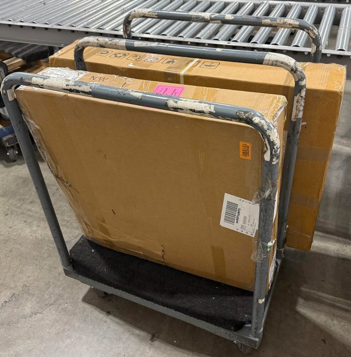 Stacked cardboard boxes on metal cart in warehouse facility
