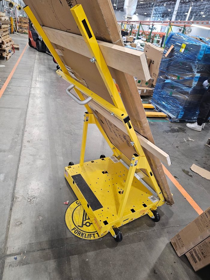 Yellow material lift with wooden panel loaded on platform