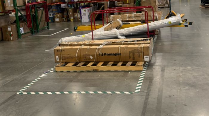 Wrapped cargo items staged in warehouse with safety tape marking