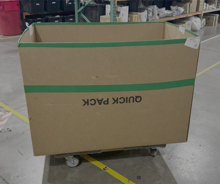 Large cardboard box on wheeled dolly in warehouse facility
