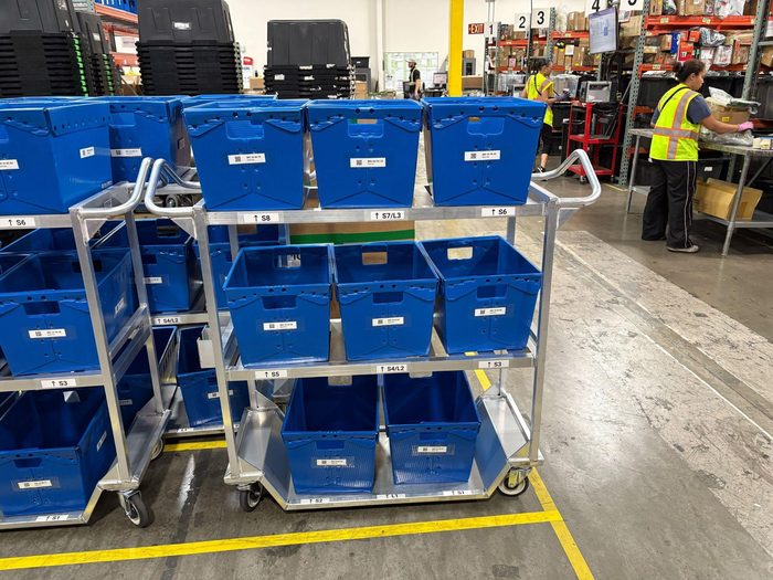 Blue plastic totes organized on mobile metal shelving racks