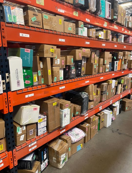 Orange industrial shelving unit stocked with cardboard boxes and merchandise