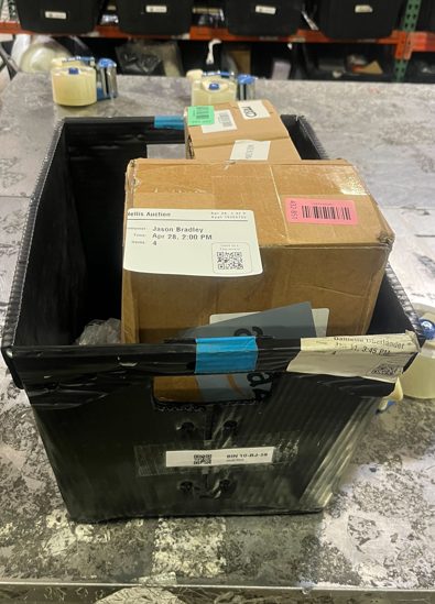 Black tote bin containing cardboard boxes and labeled packages