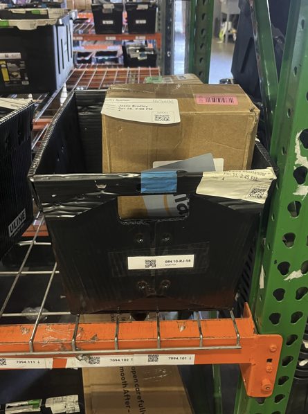 Black tote with cardboard box on orange warehouse shelf