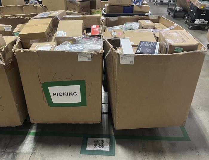 Large cardboard bins labeled for picking in warehouse setting