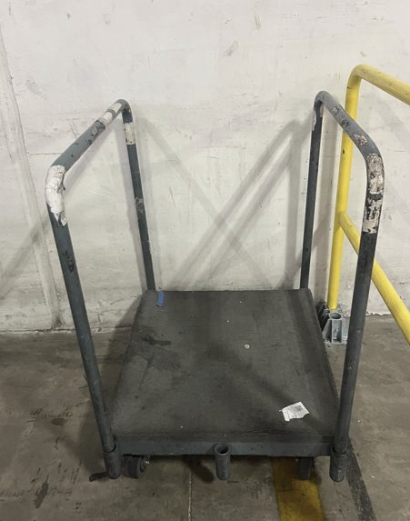 Black trampoline with yellow safety rails leaning against wall