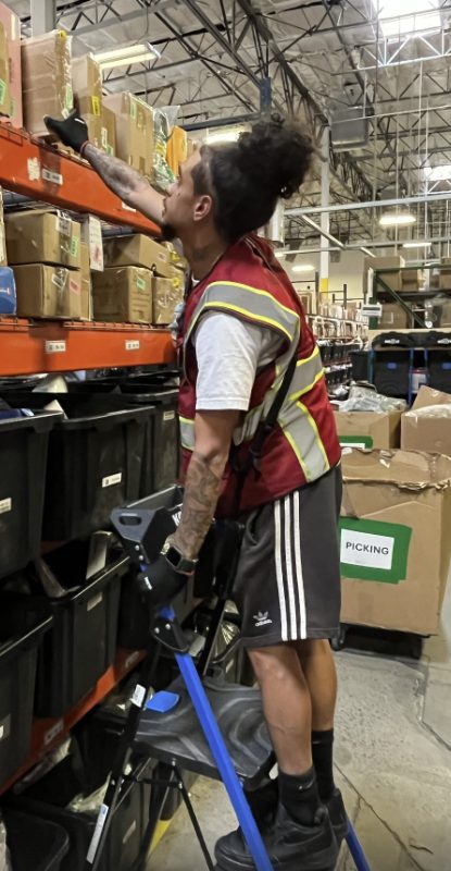 Warehouse worker picking items from orange racking shelves