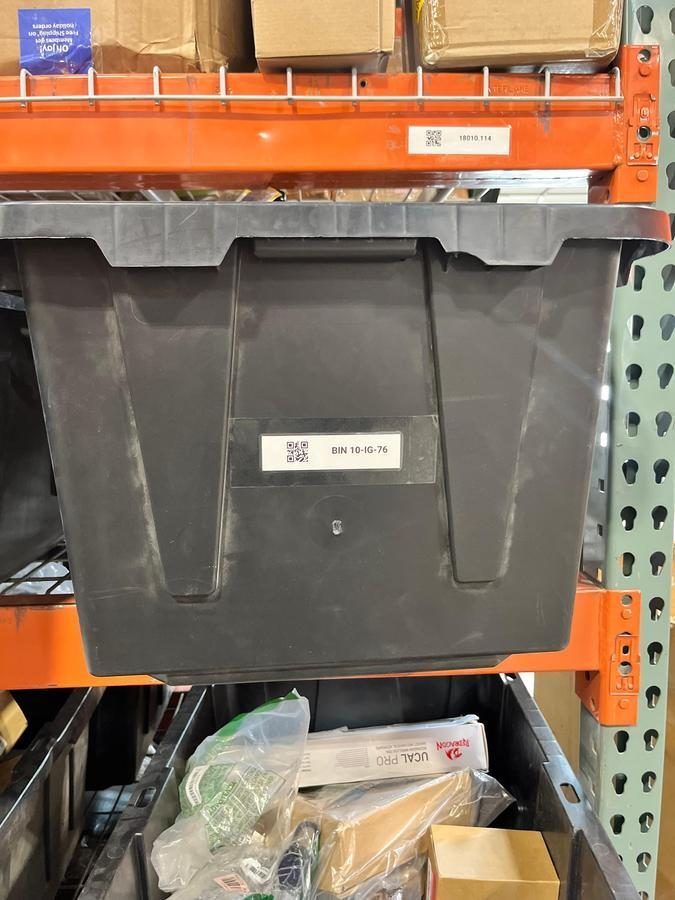 Black storage tote labeled BIN 10-16-76 on orange shelving