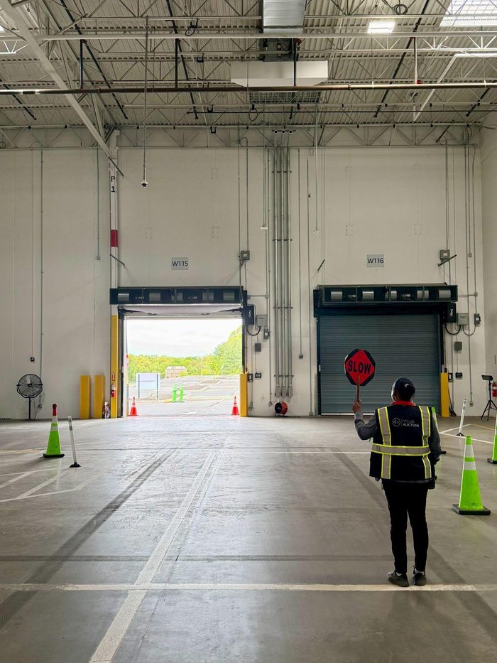 Warehouse worker conducting safety training exercise with STOP sign